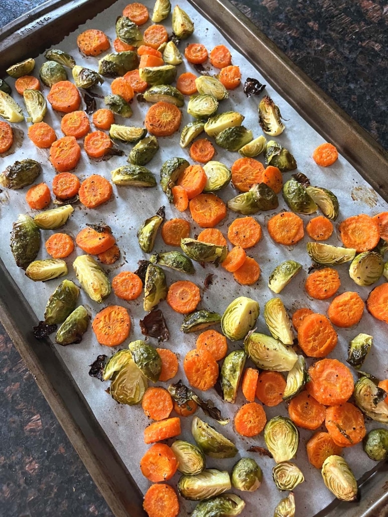 baking sheet of seasoned Brussels sprouts and carrots