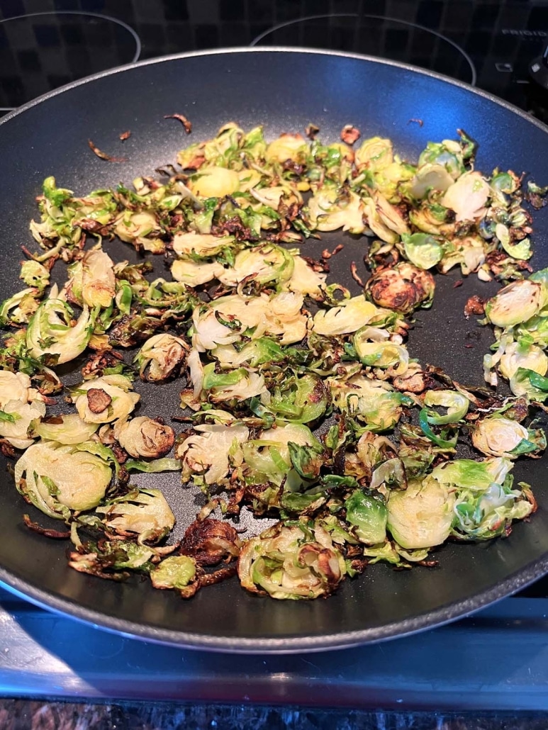 thinly sliced Brussels sprouts sautéing in a pan
