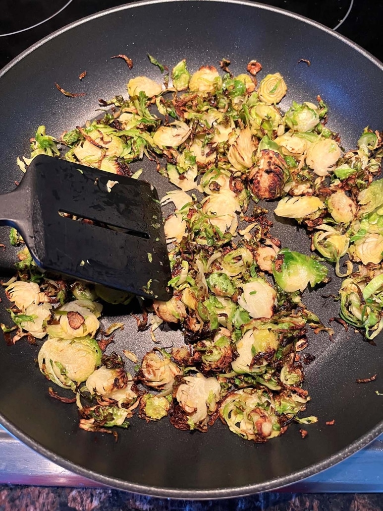 spatula stirring up healthy Sautéed Shaved Brussels Sprouts