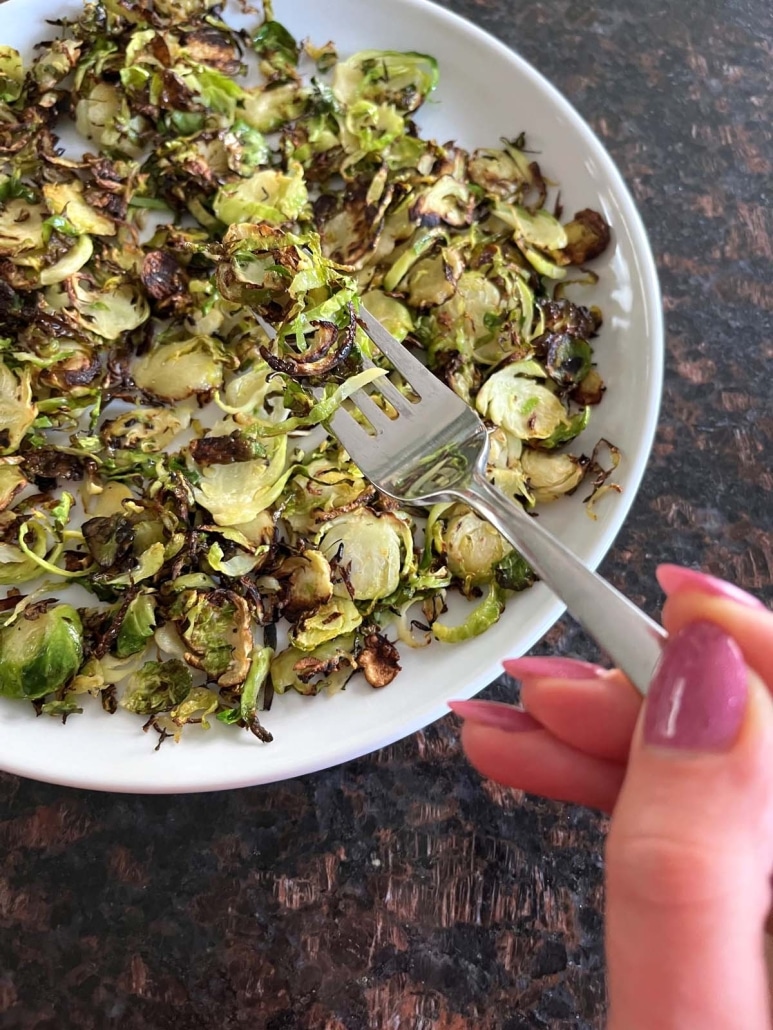 hand holding fork with bite of Sautéed Shaved Brussels Sprouts
