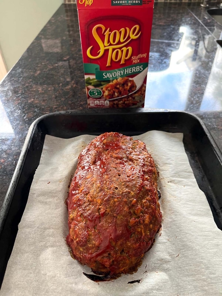 Stove Top Stuffing Meatloaf, topped with ketchup, placed next to a box of stuffing mix