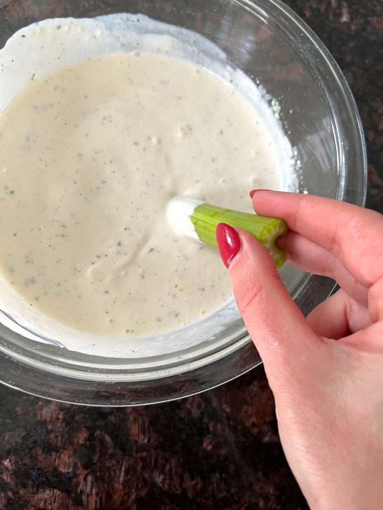 hand dipping celery into homemade ranch dip