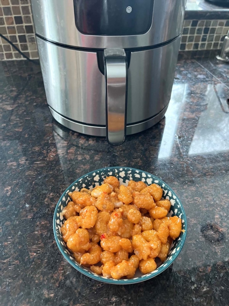 bowl of tasty bang bang shrimp in front of an air fryer