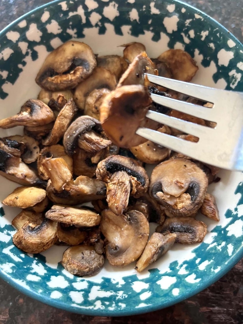 fork holding a slice of seasoned, air fried mushroom