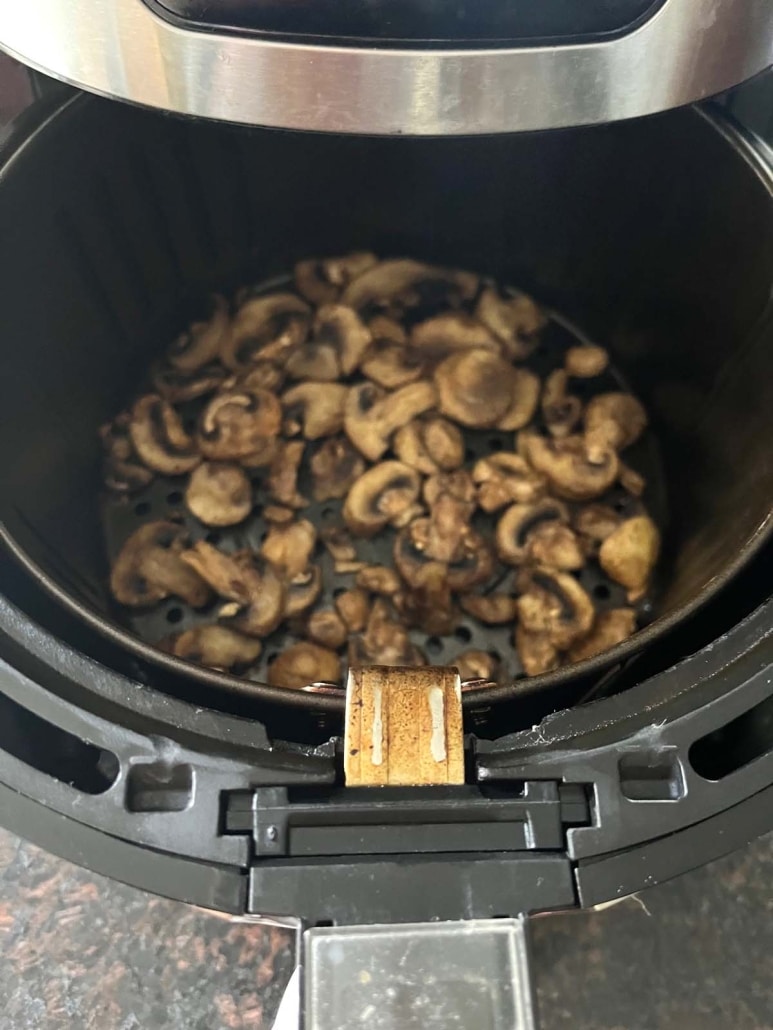 air fryer opened to show seasoned mushrooms cooking inside