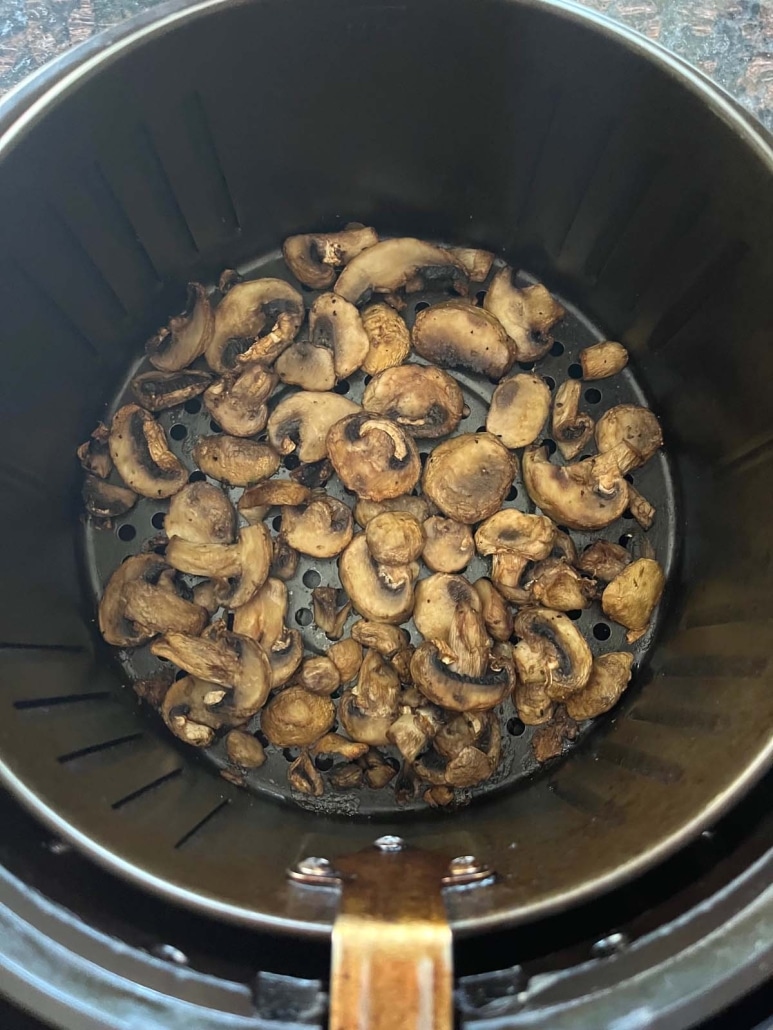 sliced, cooked mushrooms inside an air fryer basket