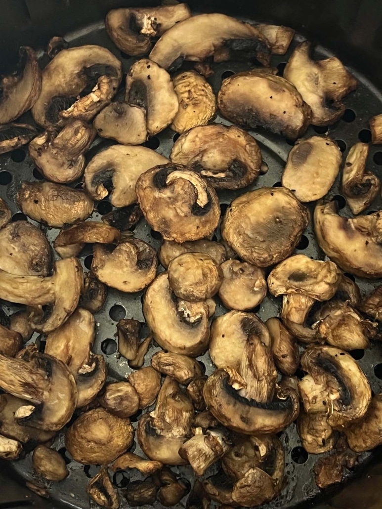 golden brown sliced mushrooms in an air fryer basket