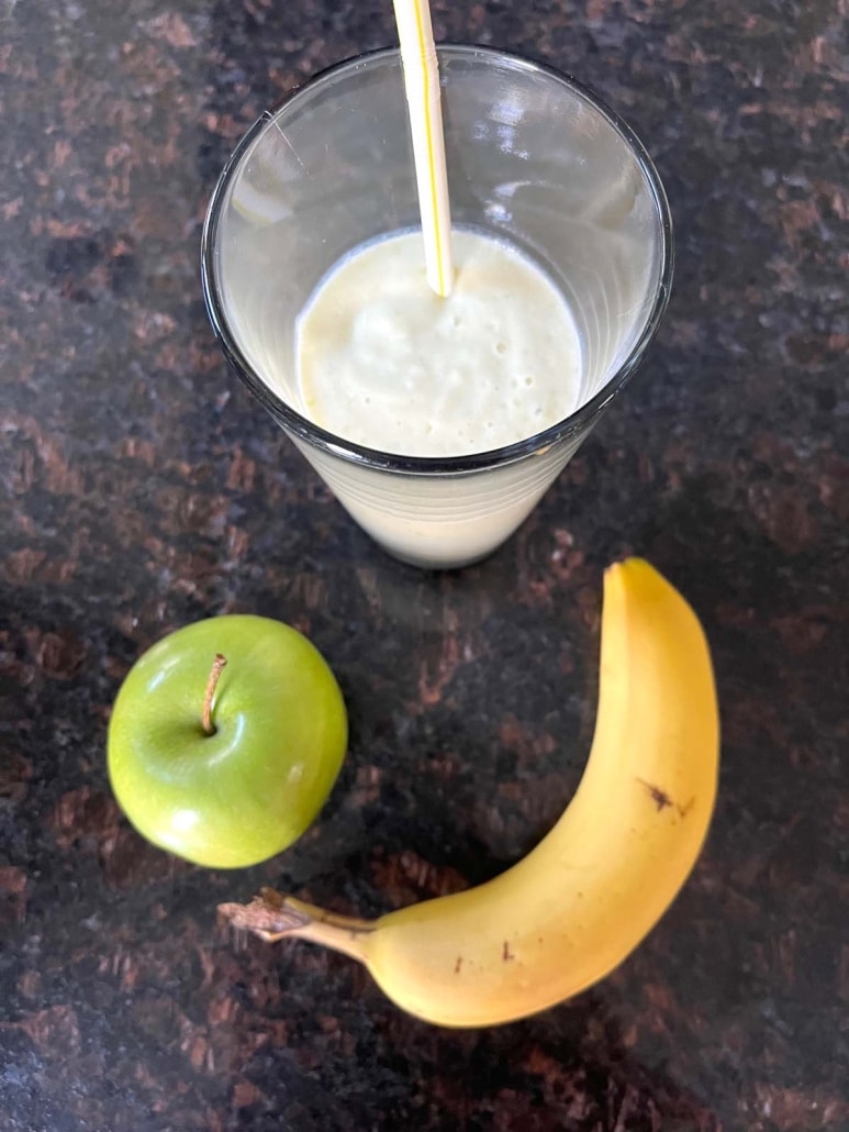 glass of Apple Banana Smoothie next to a green apple and a ripe banana