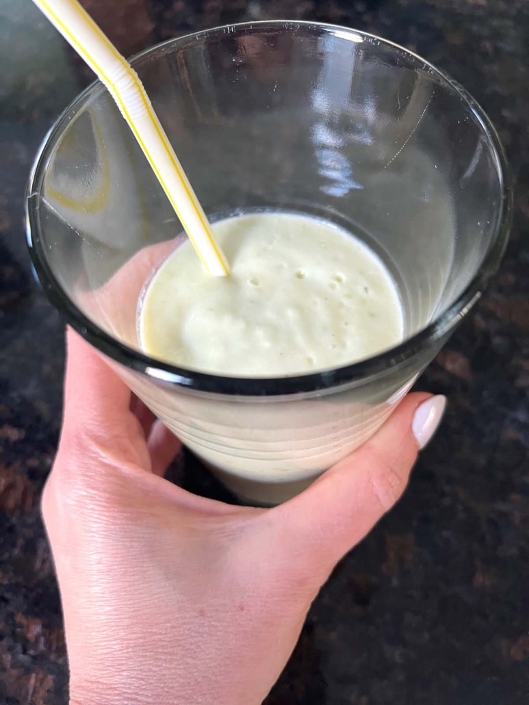 hand holding a glass of Apple Banana Smoothie