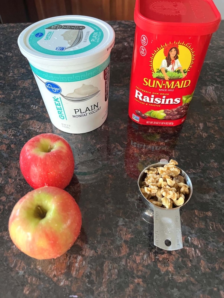 apples, Greek yogurt, raisins, and walnuts on a countertop