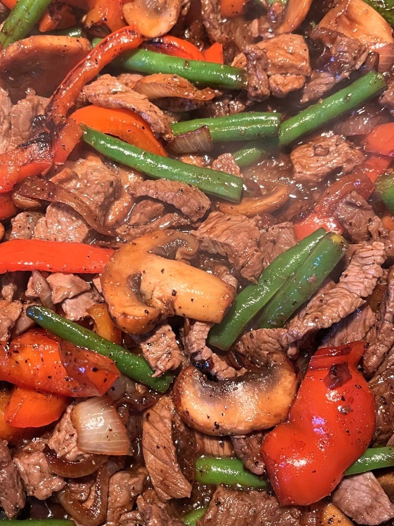 black pepper angus steak and vegetables sautéing in a skillet