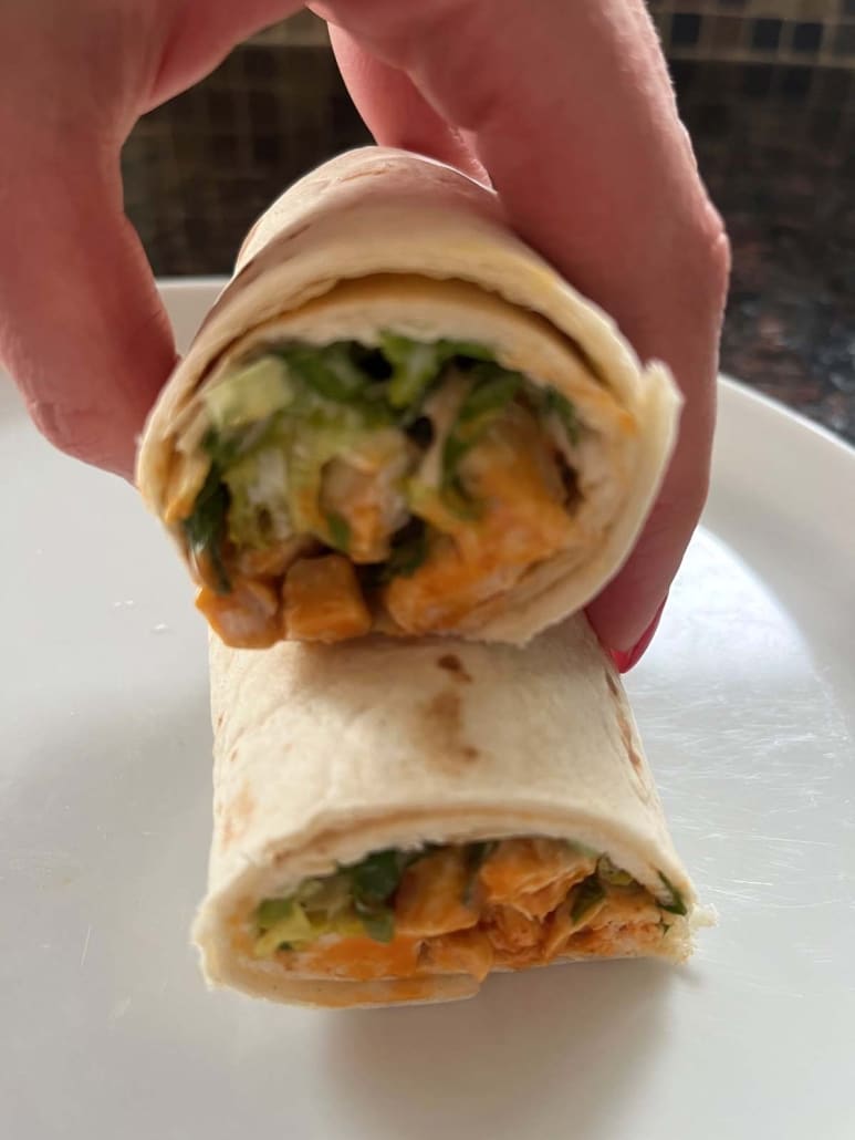 hand holding a buffalo chicken wrap with ranch dressing