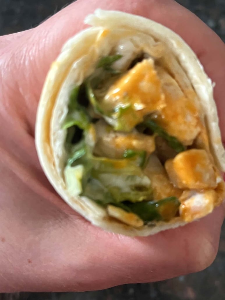 shredded lettuce and buffalo chicken in a wrap