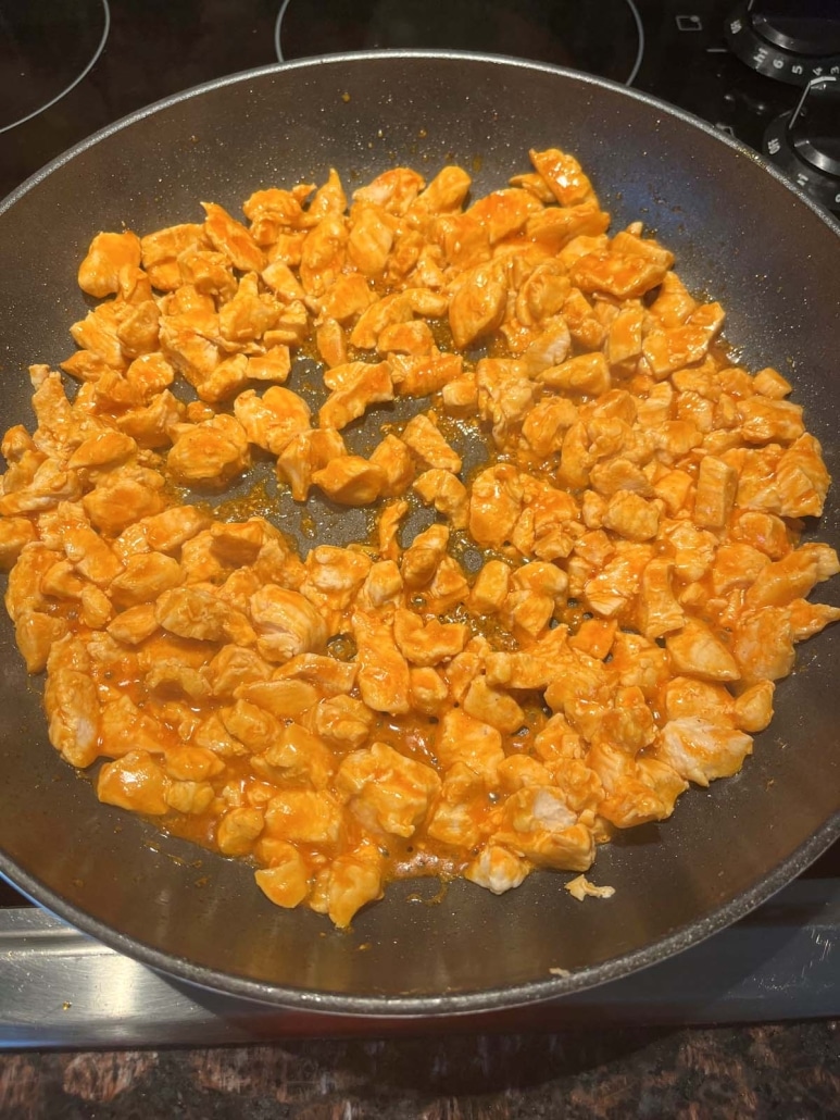 chopped chicken cooking in buffalo sauce