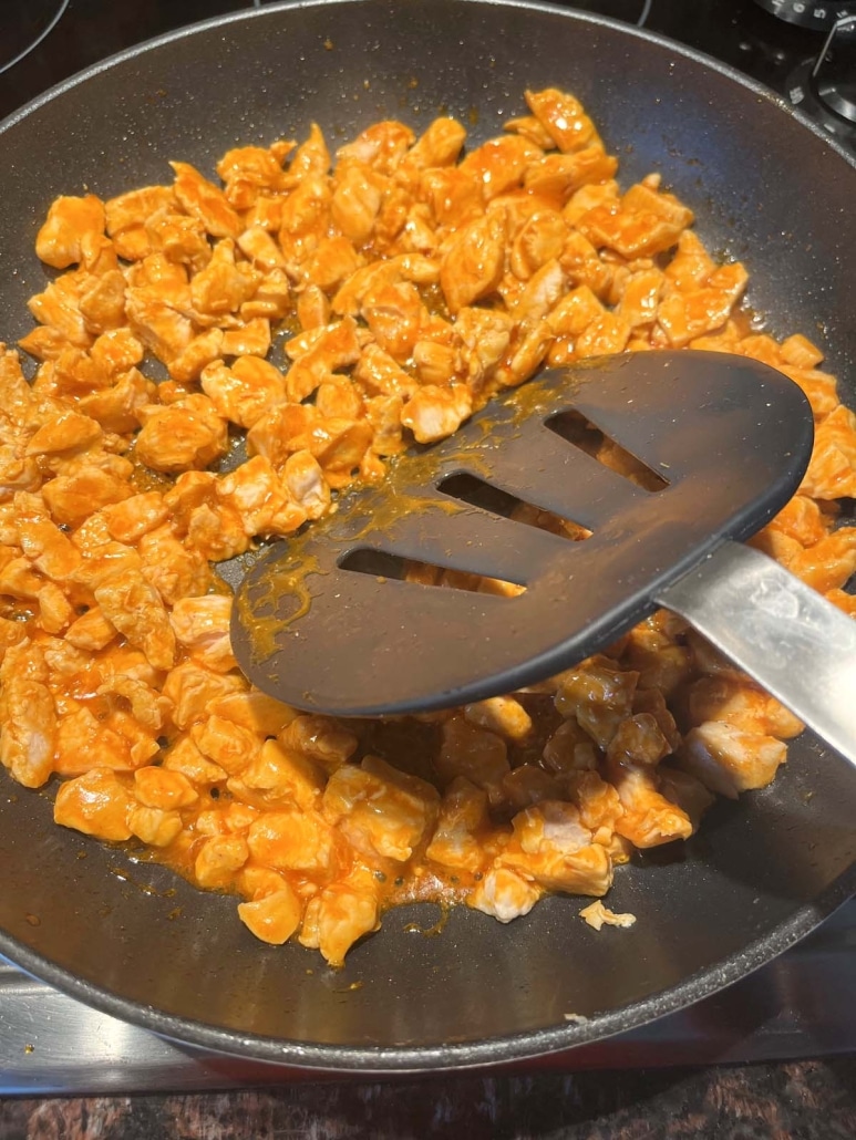 spatula mixing up buffalo chicken in a skillet