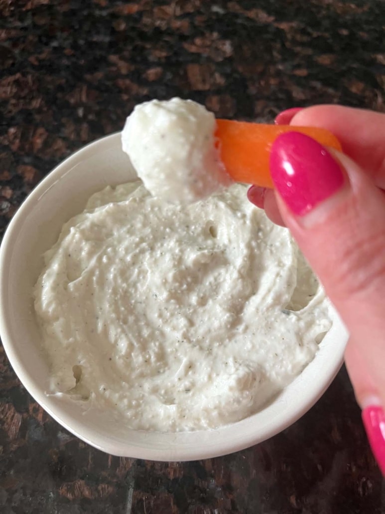 hand dipping a carrot into easy Cottage Cheese Ranch Dip