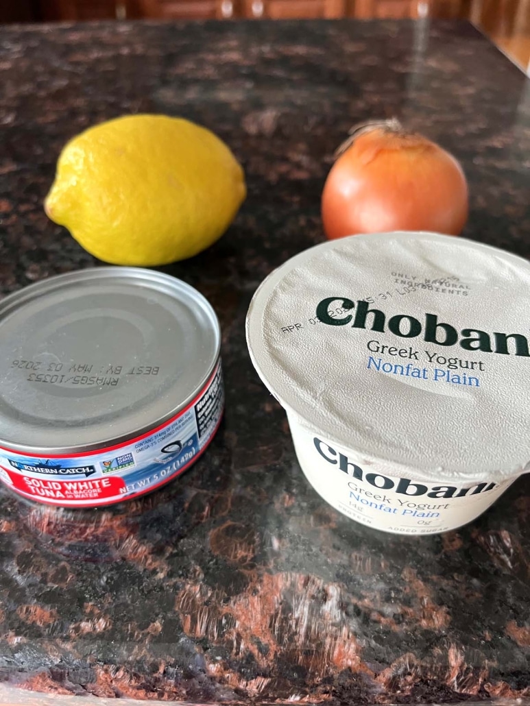 ingredients for Greek Yogurt Tuna Salad: a lemon, an onion, a can of tuna, and a container of Greek yogurt
