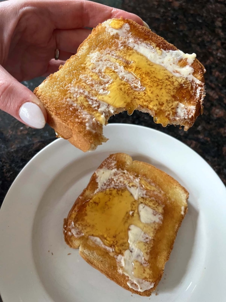 hand holding a slice of Honey Toast with a bite taken out of it