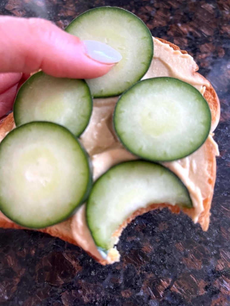 hand holding easy snack Hummus Toast with a bite taken out