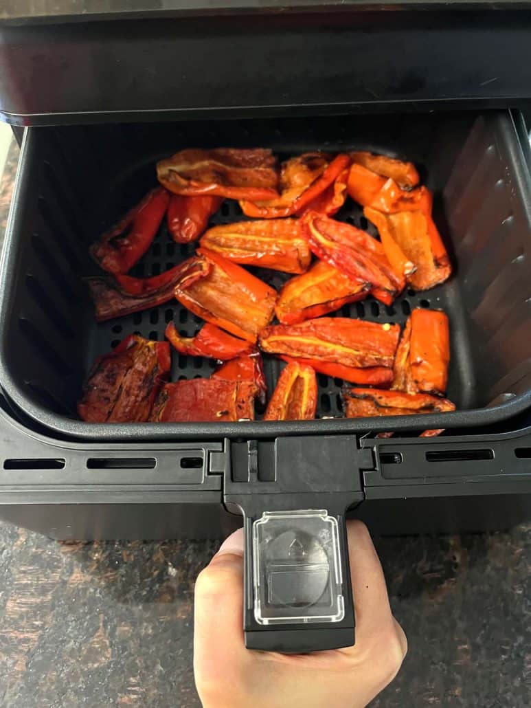 An air fryer basket filled with freshly roasted ancient red sweet peppers, perfectly charred and ready to enjoy.