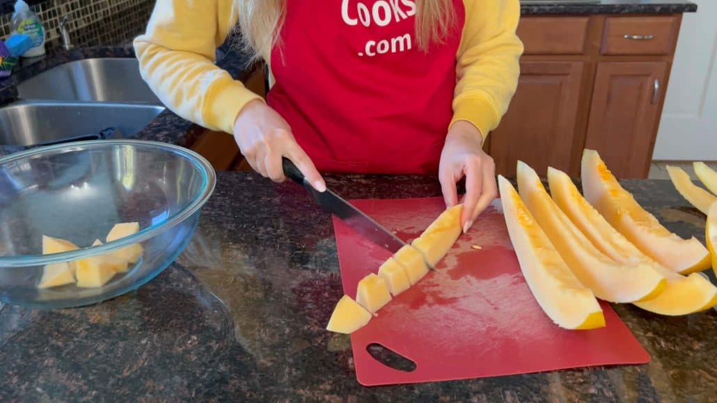 Melanie Mendelson from melaniecooks.com is cutting the Hami melon into cubes and placing them into bowl.