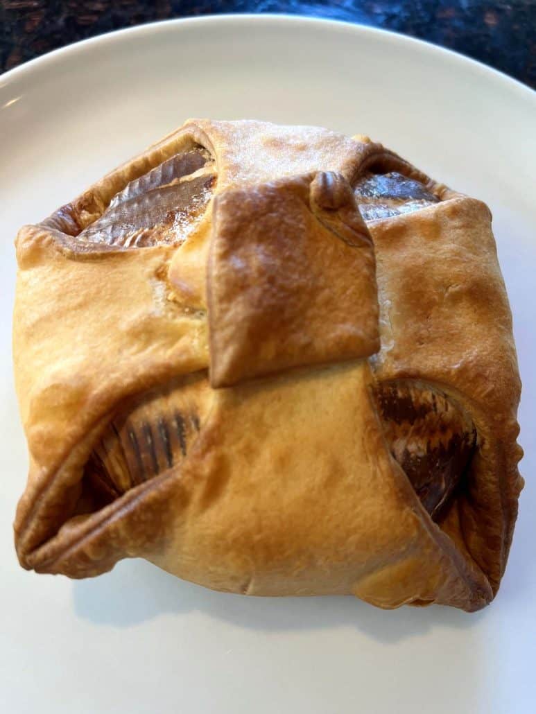 Golden brown brie en croute on a white plate, fresh from the air fryer and ready to serve.