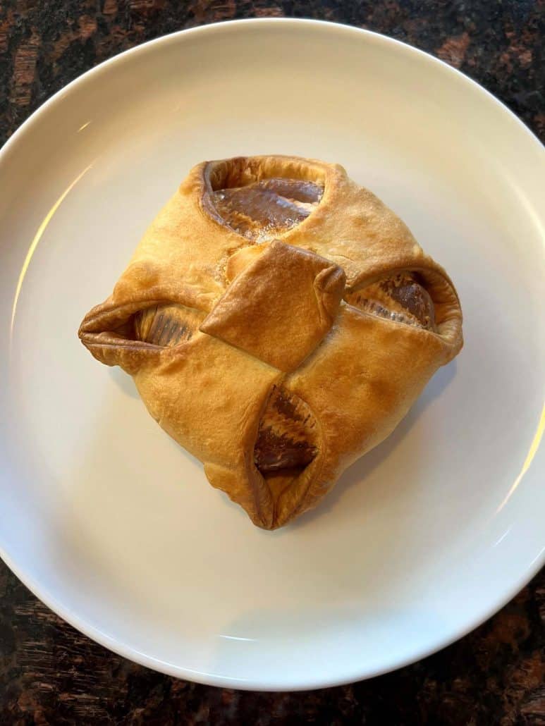 Golden air fryer brie en croute placed on a white serving plate, ready to enjoy.