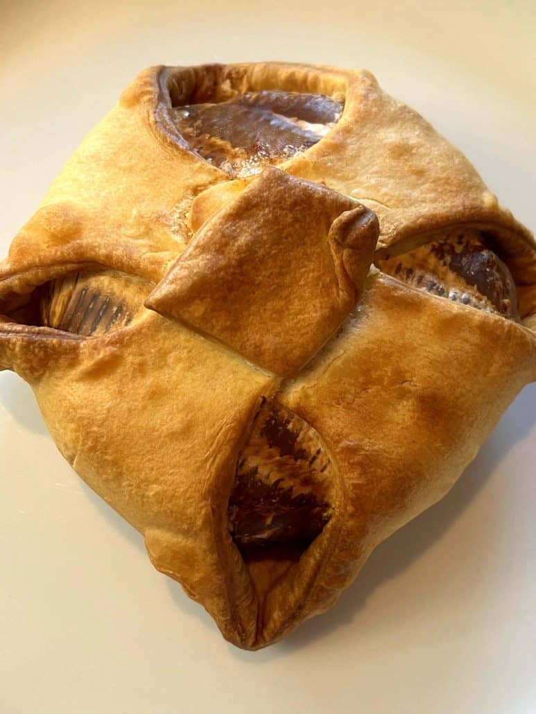 Close-up view of baked brie en croute on a plate, showing golden, flaky pastry after air frying.