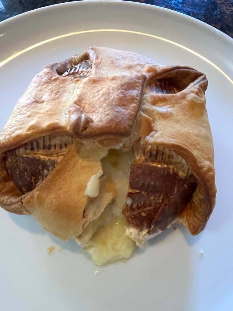 Sliced brie en croute on a plate with gooey melted cheese oozing from the golden pastry.
