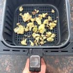 Air fryer basket filled with perfectly cooked frozen cauliflower, showing the crispy and browned results.