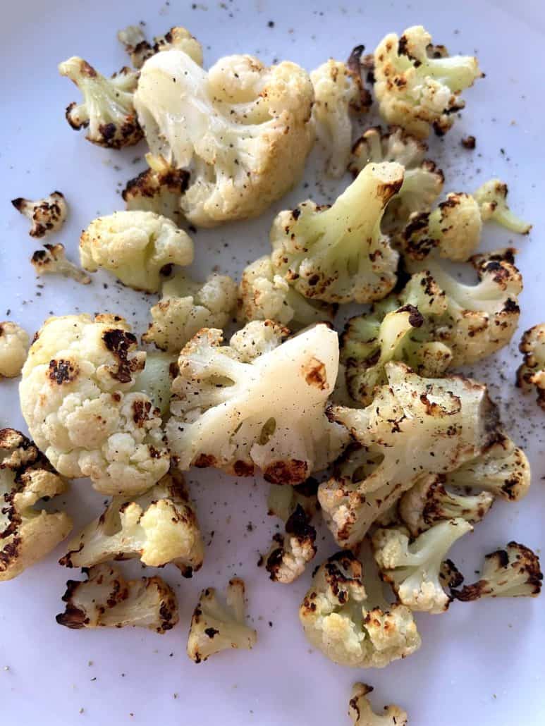Ready to serve perfectly browned air fryer cauliflower on a white plate.