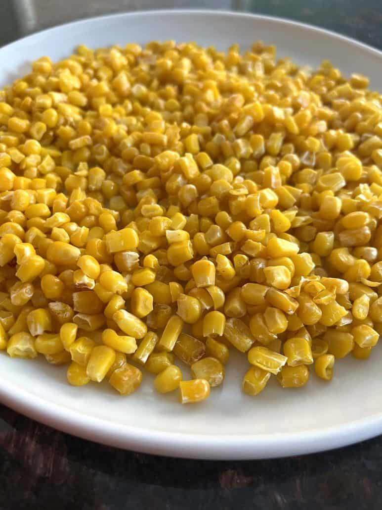 Side view of crispy air fryer corn on a white plate, showing the golden texture.