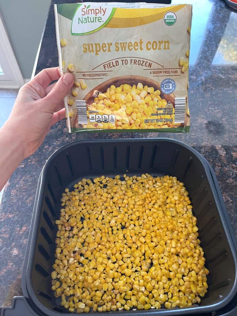 Bag of frozen super sweet corn held above an air fryer basket filled with cooked corn, showing the before and after of this easy air fryer frozen corn recipe.