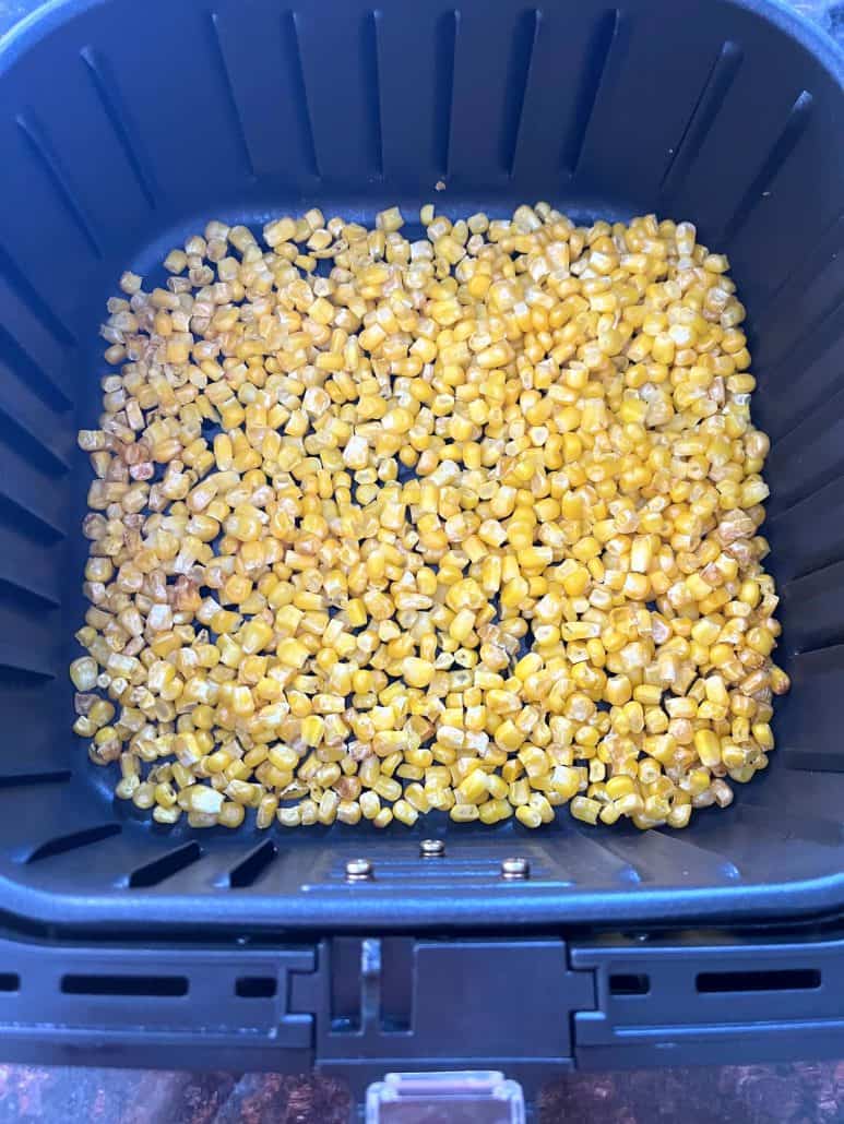 Golden, crispy cooked corn inside an air fryer basket, showing the finished result.