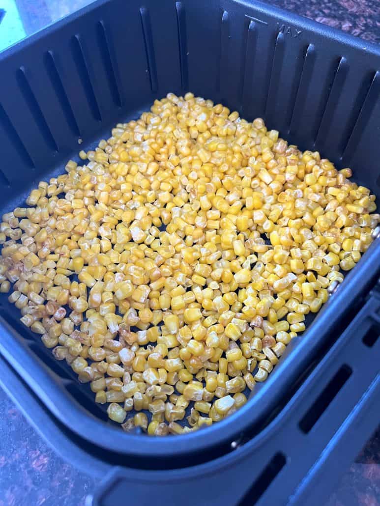 Crispy cooked corn in an air fryer basket, showing the perfect texture.