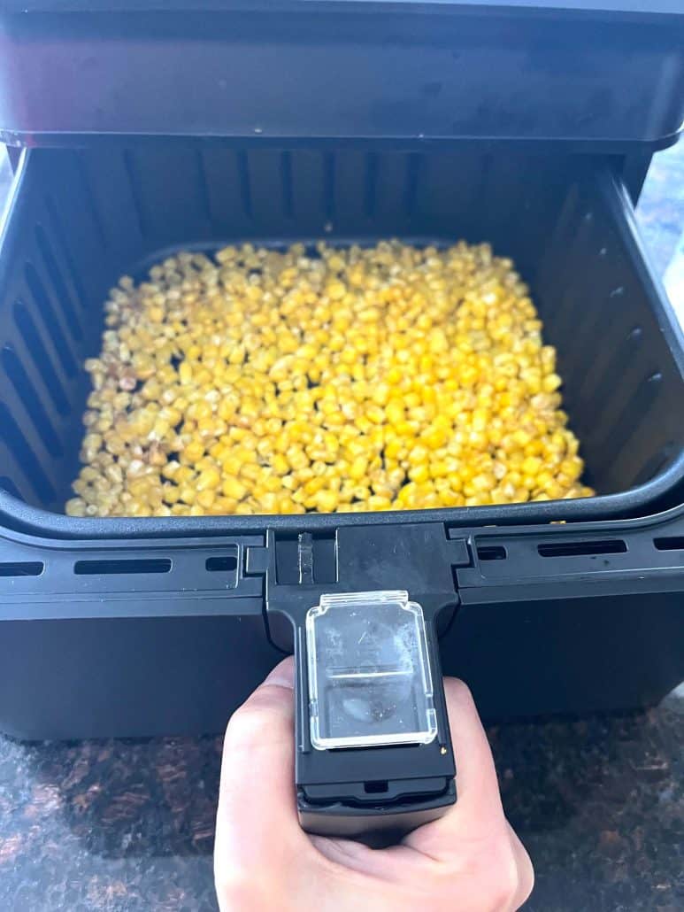 Frozen corn in an air fryer basket ready to cook an easy method for making crispy air fryer frozen corn straight from the freezer.