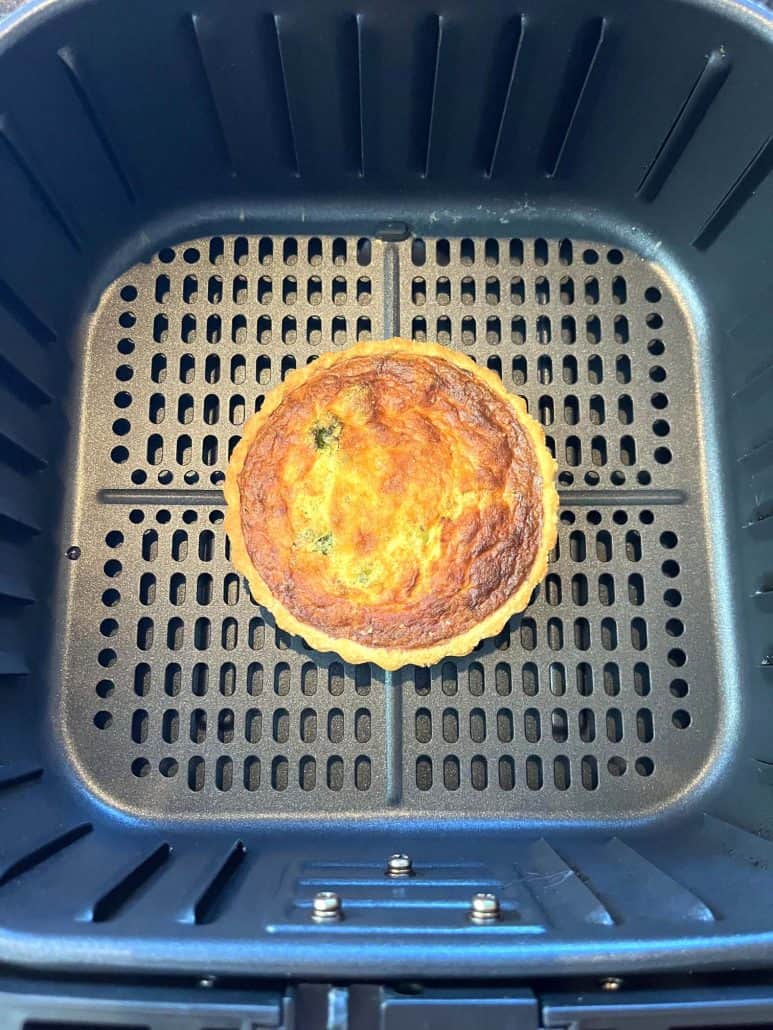 Overhead view of a fully cooked frozen quiche in the air fryer basket, showcasing the crispy, golden crust achieved with the air fryer method.