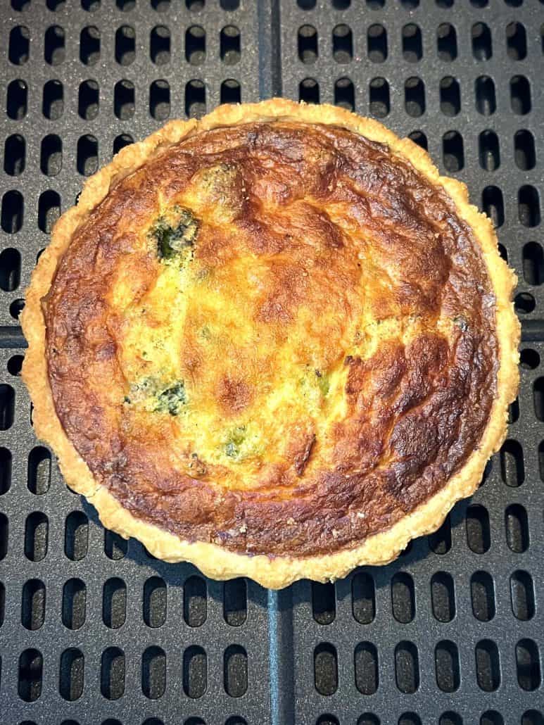 Close-up of a browned broccoli and cheddar quiche cooked in the air fryer, highlighting the flaky crust and golden top from the frozen quiche air fryer recipe.