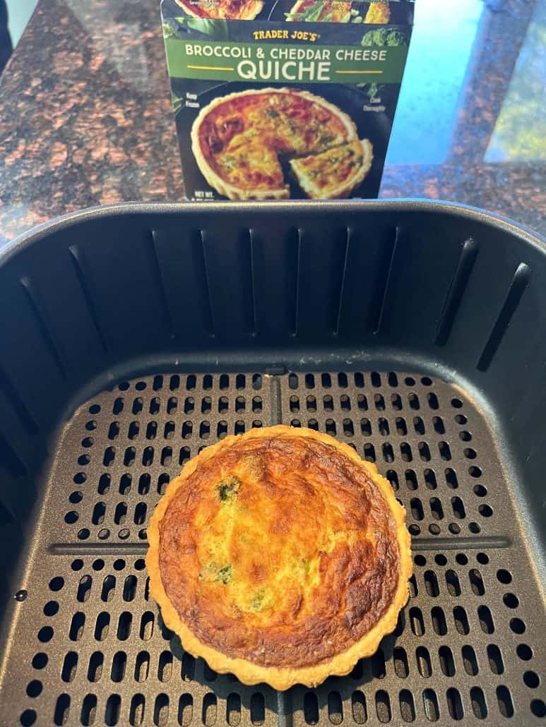 Cooked Trader Joe’s frozen quiche in the air fryer basket with packaging in the background, showing how well it turns out using this easy air fryer method.