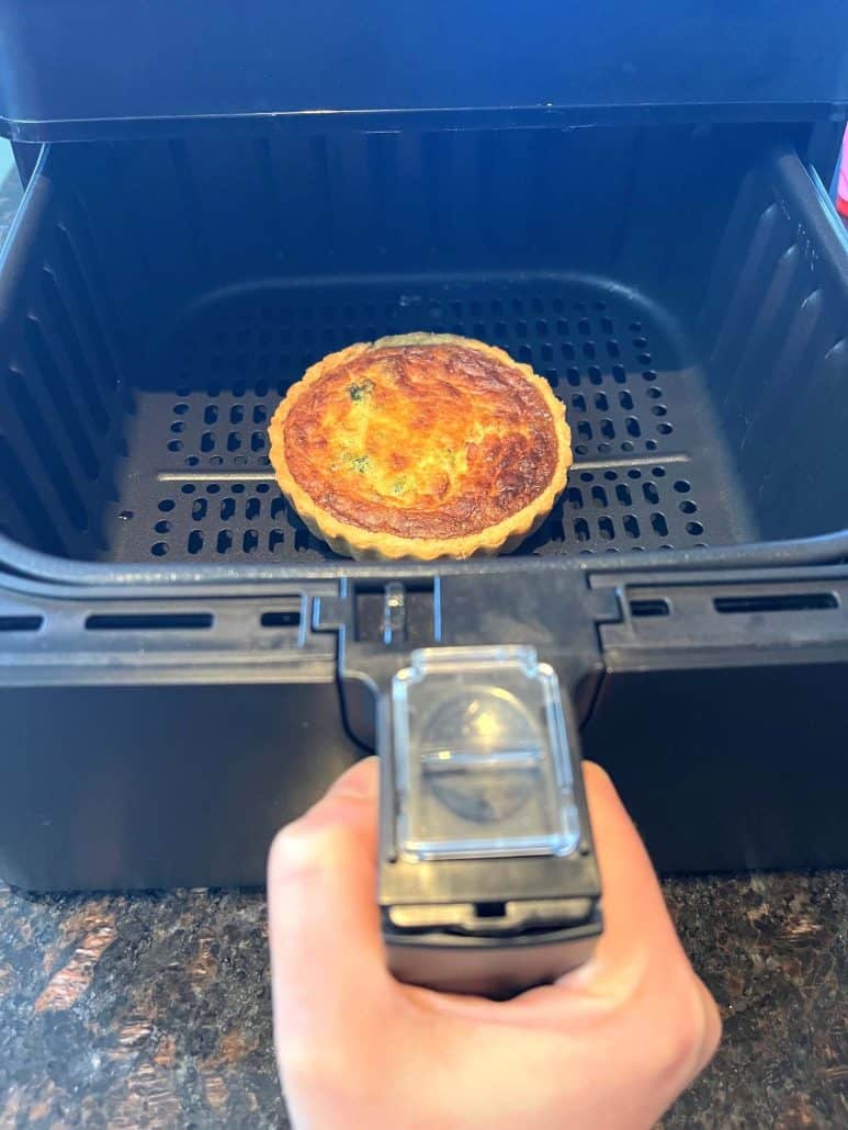 Golden-brown cooked quiche inside the air fryer basket, showing the perfect results.
