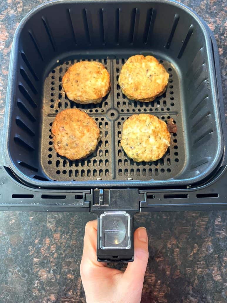 Golden-brown shrimp burgers in an air fryer basket, cooked to crispy perfection straight from frozen.
