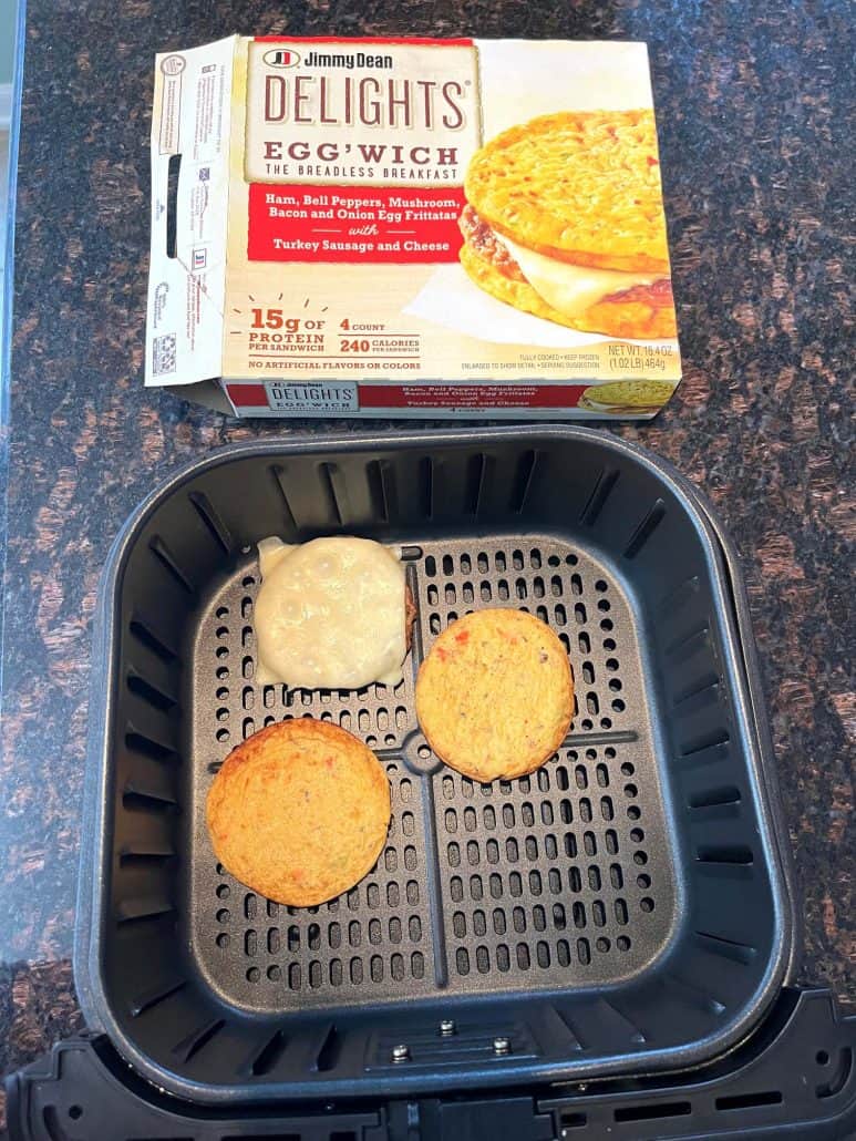 Jimmy Dean Delights Egg’wich cooking in the air fryer with its box nearby.
