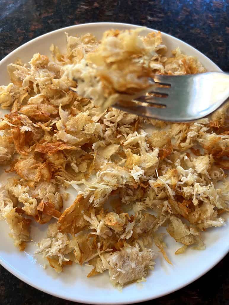 Fork picking up a bite of crispy, golden air fryer shaved chicken breast from a plate—showcasing the perfect texture of this quick and easy protein option.