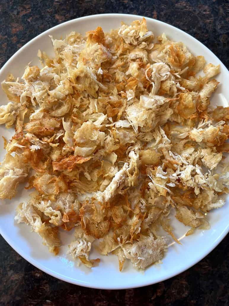 Plate of cooked shaved chicken breast, fresh from the air fryer—golden, juicy, and ready to serve as a quick protein for wraps, salads, or dinner bowls.