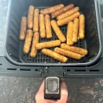 Air fryer basket filled with crispy, golden-brown mozzarella sticks, freshly cooked and ready to serve.