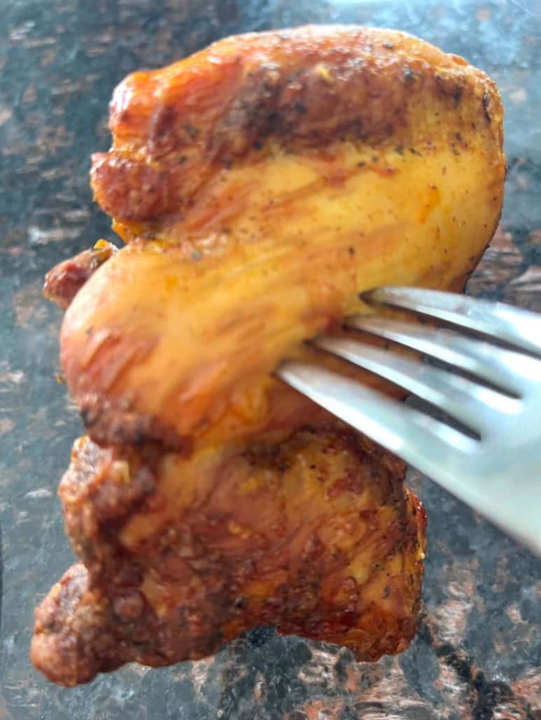 Close-up of a cooked Trader Joe’s Shawarma Chicken Thigh held with a fork, showing crispy and juicy texture.