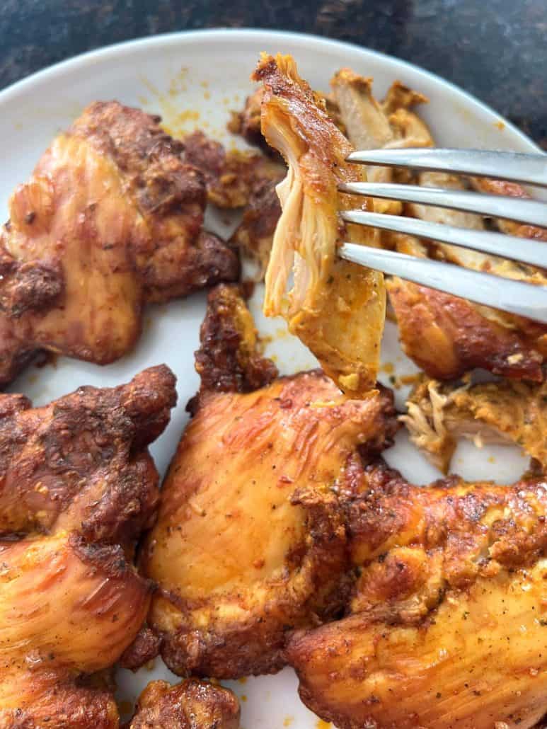 Juicy Trader Joe’s Shawarma Chicken Thighs on a plate, with a fork holding a tender sliced piece ready to eat.