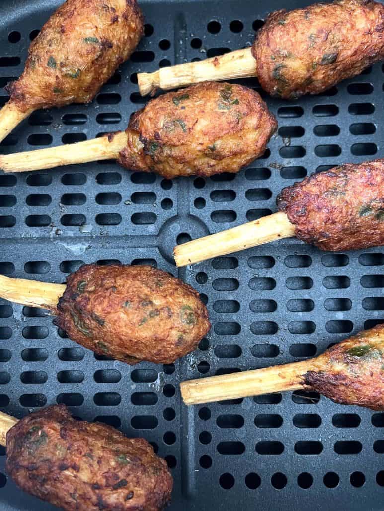 Close-up of golden brown Chao Tom on sugarcane sticks inside the air fryer basket.