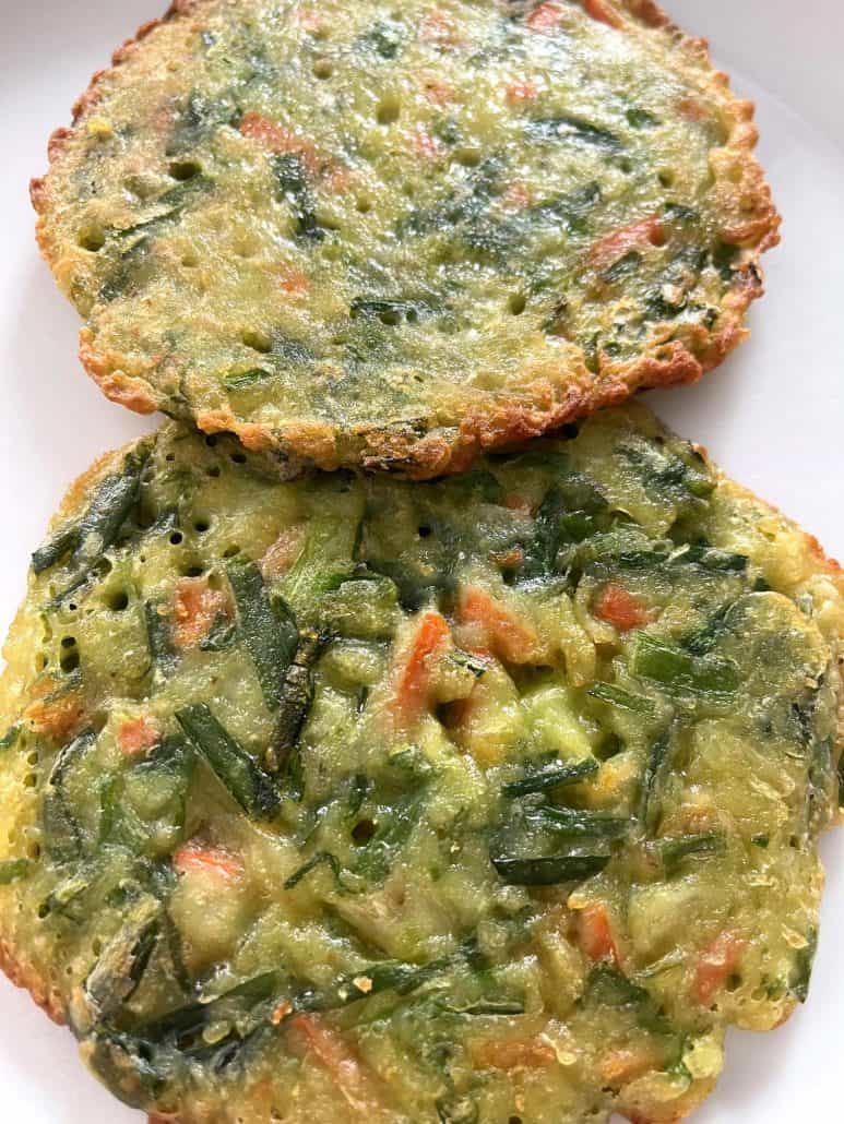 Close-up of two crispy Trader Joe’s scallion pancakes on a white plate, showing their golden edges and savory green onion filling.