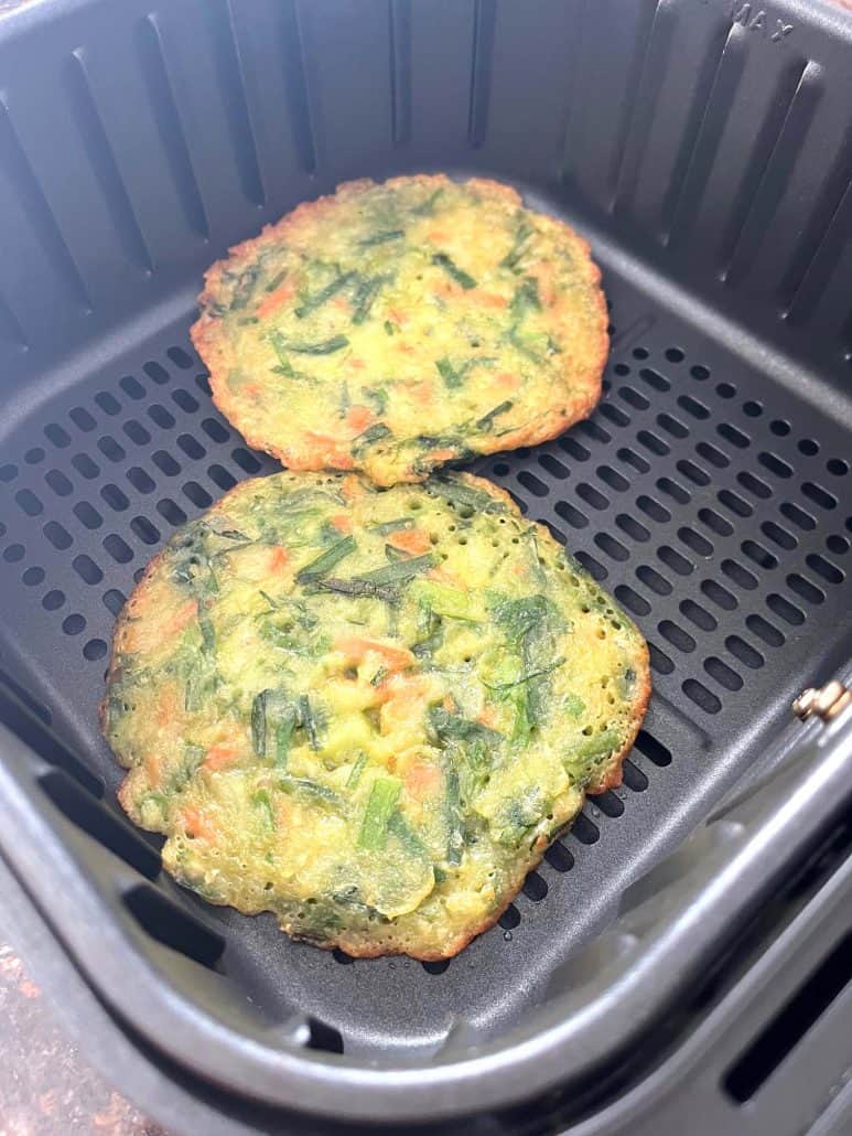 Two Trader Joe’s scallion pancakes freshly cooked in the air fryer basket, showing their crispy edges.